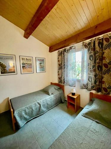 une chambre avec deux lits et une fenêtre dans l'établissement Le Râteau Bavoir, à Calvi