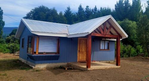 a small blue house with a tin roof at Cabaña Antü Küyen Melipeuco 02 in Melipeuco