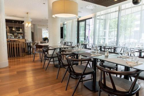 a dining room with tables and chairs and windows at Residence Inn by Marriott Toulouse-Blagnac in Blagnac