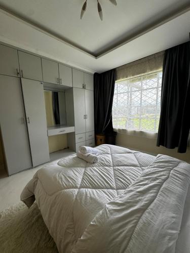 a bedroom with a large white bed and a window at Cottage Ragati in Nanyuki