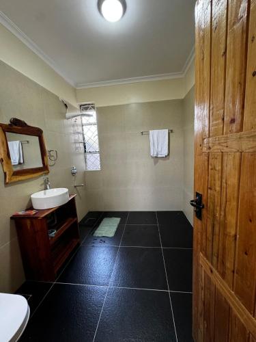a bathroom with a sink and a wooden door at Cottage Ragati in Nanyuki