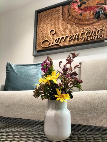 a white vase filled with flowers on a table at Vesuvio Inn Bed & Wine Experience in Boscotrecase