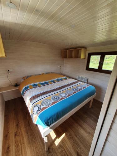 - un lit dans l'angle d'une petite chambre dans l'établissement La roulotte de Rochavelle, à Chiché