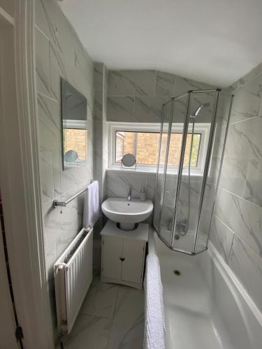a white bathroom with a sink and a shower at Spacious Home, Garden, in Harlow, Comfy for Contractors & Relocators in Great Parndon