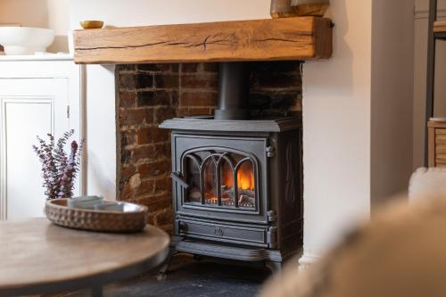a wood stove in a living room with a table at Charming 2 Bed Cottage - within city walls - free parking- garden in Canterbury