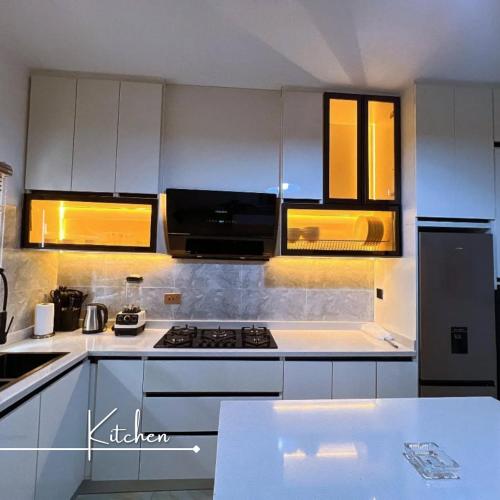 a kitchen with white cabinets and a stove top oven at Desireé by StayHub - Luxury 3 Bedroom with PS5 in Jahi in Abuja