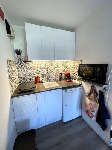une petite cuisine avec des armoires blanches et un évier dans l'établissement T2 Vue Mer à 30m de la Plage, à Villers-sur-Mer