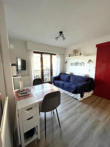 - une chambre avec un lit bleu et un bureau avec des chaises dans l'établissement T2 Vue Mer à 30m de la Plage, à Villers-sur-Mer