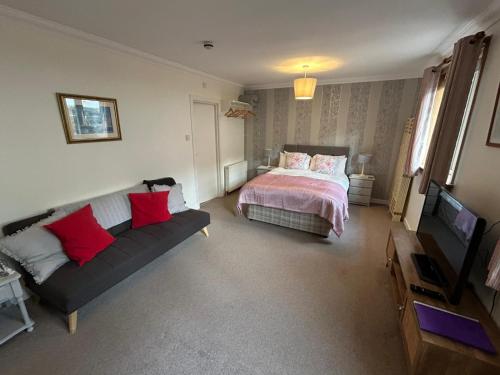 a bedroom with a bed and a couch and a tv at Elderslie Guest House in Oban