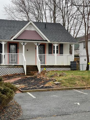 a white house with a porch and a driveway at Gingerbread House Inn - We Are Open - Winter, Spring, Summer and Fall in Wolfville