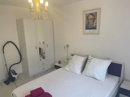 sypialnia z białym łóżkiem i żyrandolem w obiekcie Holiday Home 1 w Bibinje