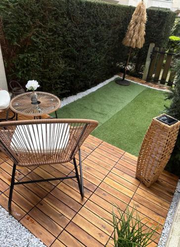 une terrasse en bois avec une table, des chaises et une pelouse dans l'établissement Premium & Cosy Studio - Paris à 20 mins - Châteaux de Versailles à 8 mins, à Le Chesnay