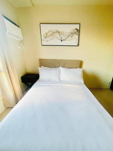 una camera da letto con un letto bianco con un quadro sul muro di B3 Chic Sunset Studio Escape a Città di Iloilo