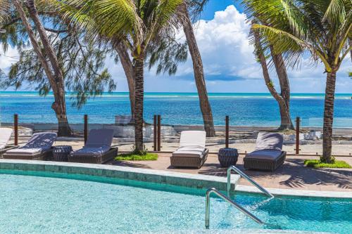 a swimming pool with chaise lounge chairs and the ocean at Oceana Atlântico Hotel & SPA in João Pessoa