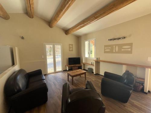 a living room with leather furniture and a tv at Villas de La Ferme Du Gros Noyer in Malaucène