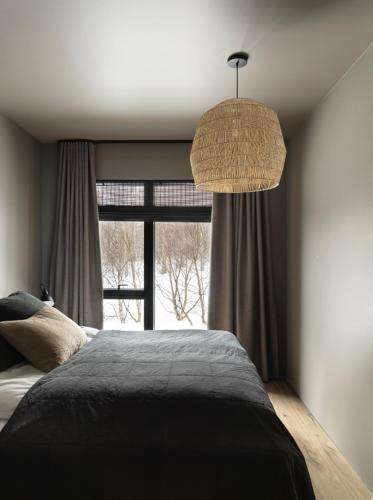 a bedroom with a bed and a large window at Svart Lodge in Akureyri
