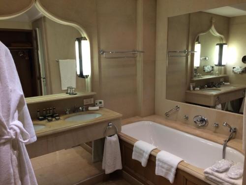 a bathroom with a tub and a sink and a mirror at Hotel de la Cité Carcassonne - MGallery Collection in Carcassonne