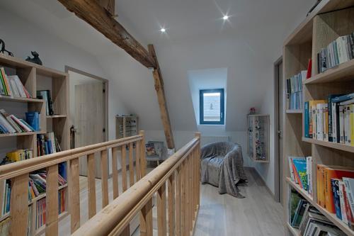 a hallway with wooden bookshelves and a staircase with books at Ferme des Petites Oreilles 4 étoiles in Montignac