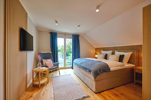 a bedroom with a bed and a tv and a chair at Lykke Hus - Traumhaus für bis zu 10 Personen in Timmendorfer Strand