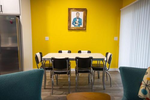a table and chairs in a room with a yellow wall at Retro Rose Retreat-Rose District in Broken Arrow