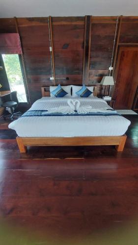 a bedroom with a large bed with blue pillows at Why Worry Homestay & Café in Ban Talat Khwai