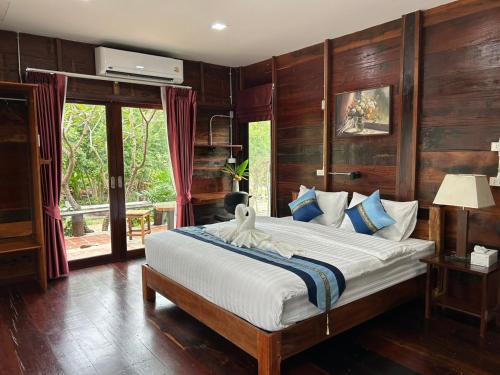 a bedroom with a large bed with wooden walls at Why Worry Homestay & Café in Ban Talat Khwai