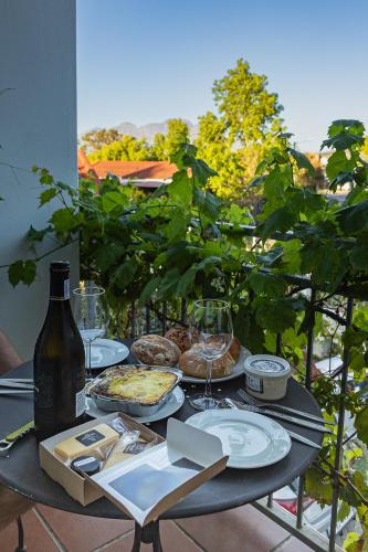 a table with plates of food and a bottle of wine at Penelope's Stellenbosch in Stellenbosch