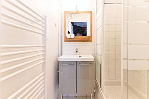 une salle de bain blanche avec un lavabo et un miroir dans l'établissement Beautiful bright apartment in Paris, à Paris