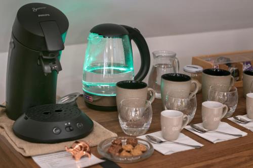 a kitchen counter with a coffee maker and glasses of water at Ferme des Petites Oreilles 4 étoiles in Montignac
