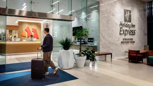 a man walking through a lobby with a suitcase at Holiday Inn Express Singapore Orchard Road by IHG in Singapore