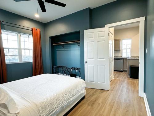 a bedroom with a white bed and blue walls at StayAE Downtown - One Bedroom, 2nd Floor in Baton Rouge