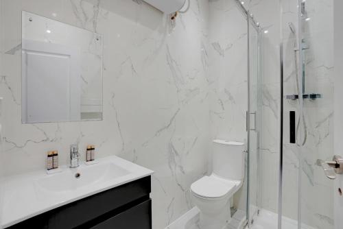une salle de bain blanche avec toilettes et douche dans l'établissement Modern Apartment -Accor Arena Bercy 1BR-4P, à Paris