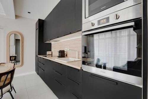 - une cuisine avec des placards noirs et un évier dans l'établissement Modern Apartment -Accor Arena Bercy 1BR-4P, à Paris