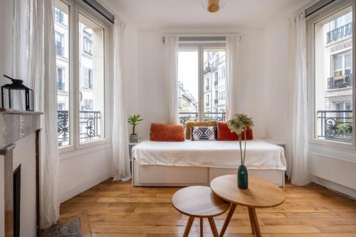 a bedroom with a bed and a table and windows at Cosy Apartment with 270 degrees view on Paris streets in Paris