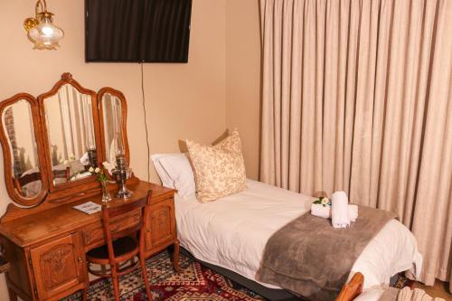 a bedroom with a bed and a desk with a mirror at Diamantvallei Landgoed in Rayton