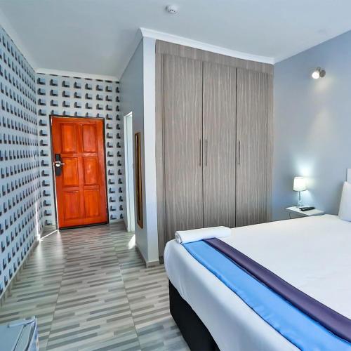 a bedroom with a bed and a red door at Avrila Springs Hotel in Gaborone