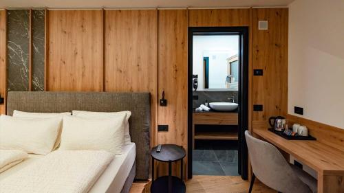 a bedroom with a bed and a bathroom with a sink at Dolomites Room and Breakfast Formiè in Vigo di Fassa