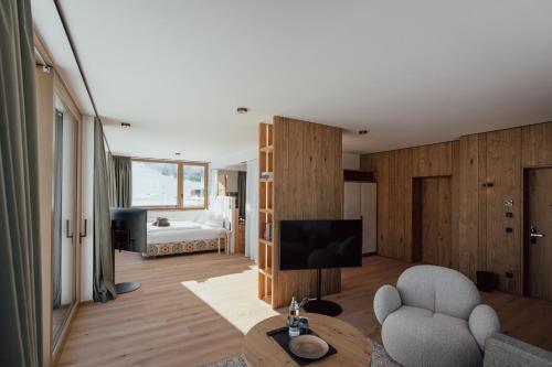 a living room with a television and a room with a bed at Hotel Auszeit in Pertisau