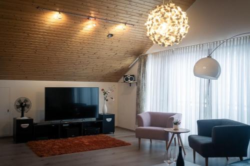 a living room with a television and a couch and chairs at Ludwigshafen Traumvilla in Ludwigshafen am Rhein