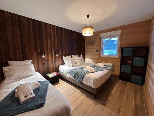 a bedroom with two beds and a window at Chalet PLUME D'EAU - jacuzzi, piscine et pétanque in Gerbépal