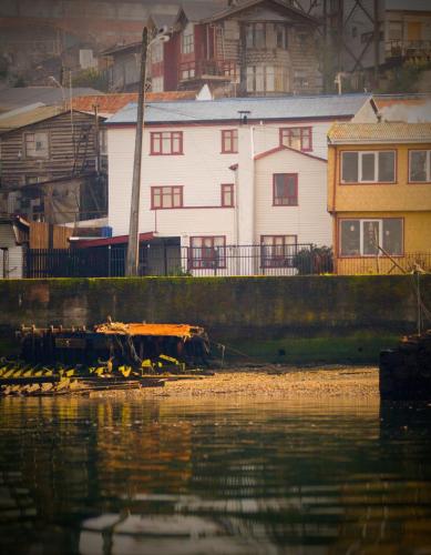 a white building next to a body of water at Casa Chiloe hostel in Castro