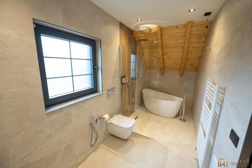 a bathroom with a tub and a toilet and a window at PineHill Hotel, Restaurant , Pool & Spa - RAZEM in Razëm