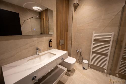 a bathroom with a white sink and a toilet at PineHill Hotel, Restaurant , Pool & Spa - RAZEM in Razëm