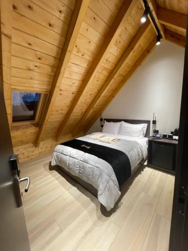 a large bed in a room with wooden ceilings at PineHill Hotel, Restaurant , Pool & Spa - RAZEM in Razëm