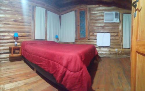 a bedroom with a red bed in a log cabin at Cabañas - sierras de cordoba - Jose de la quintana #2 in José de la Quintana