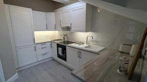 a kitchen with white cabinets and a sink at Spacious & stylish upgraded 1BD Malahide Marina in Malahide