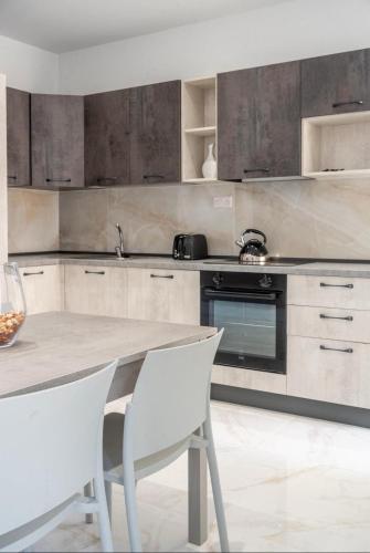 a kitchen with a table and two white chairs at 2 bedroom apartment in gudja in Gudja