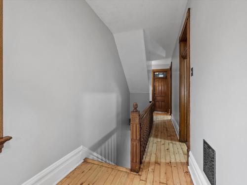 a hallway with white walls and a wooden stairway at Oakland, Pittsburgh !B Stylish and Quiet Private Bedroom with Shared Bathroom in Pittsburgh
