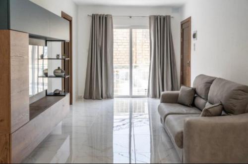 a living room with a couch and a large window at 2 bedroom apartment in gudja in Gudja