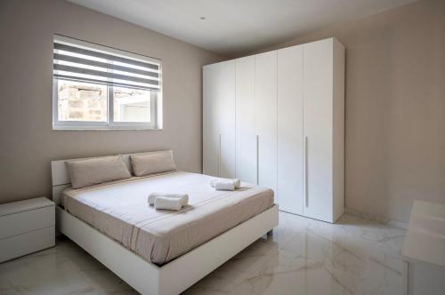 a bedroom with a white bed and a window at 2 bedroom apartment in gudja in Gudja